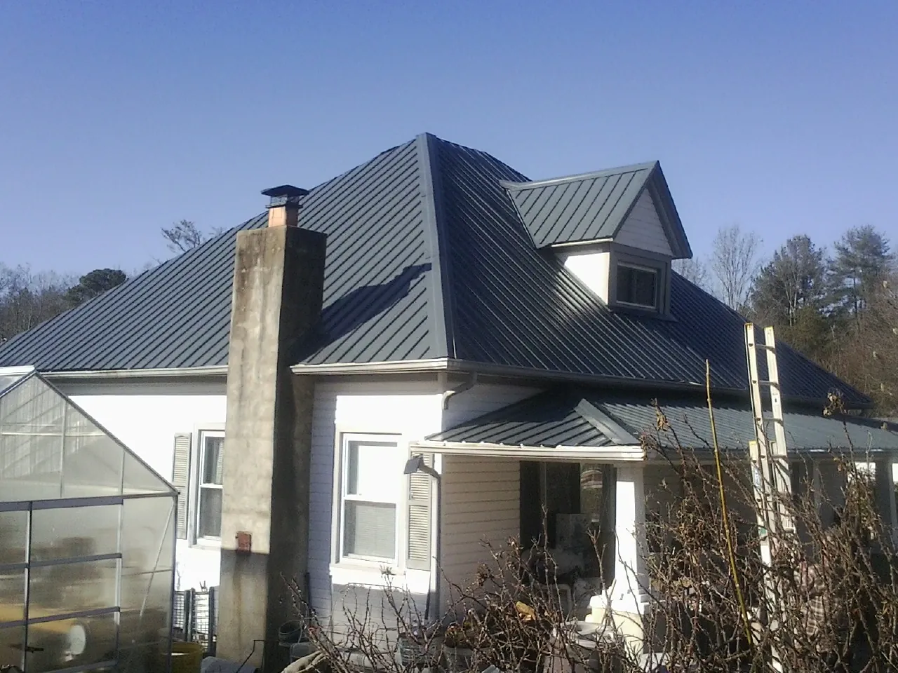 Dark blue standing seam metal roof on a white farmhouse with dormer — Slate & Tile Roof Repair by Roofing Brothers in Huguenot
