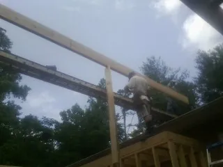 Carpenter setting a ridge beam over a new addition frame — Ice Dam Removal by Roofing Brothers in Huguenot
