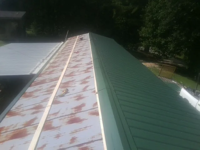 Old rusted panels beside newly installed green metal roofing — Wind Damage Roof Repair by Roofing Brothers in Huguenot
