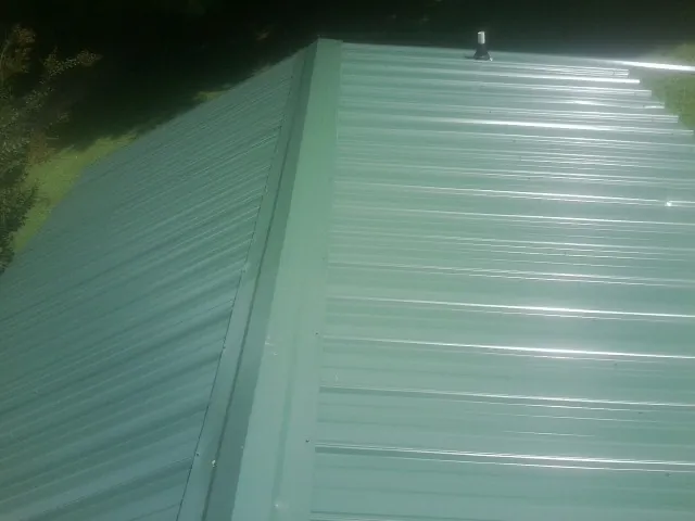 New green metal panels meeting at the ridge of a roof — Flat Roof Repair work by our crew in Huguenot