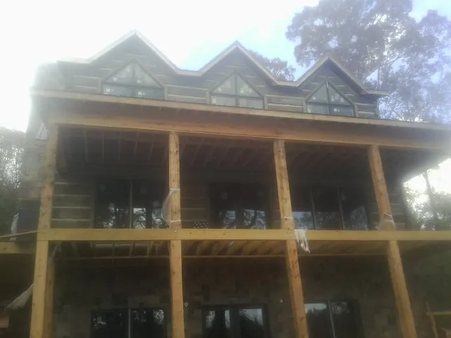 Dormers and porch framing on a large log home under construction — Roof Coating work by our crew in Huguenot