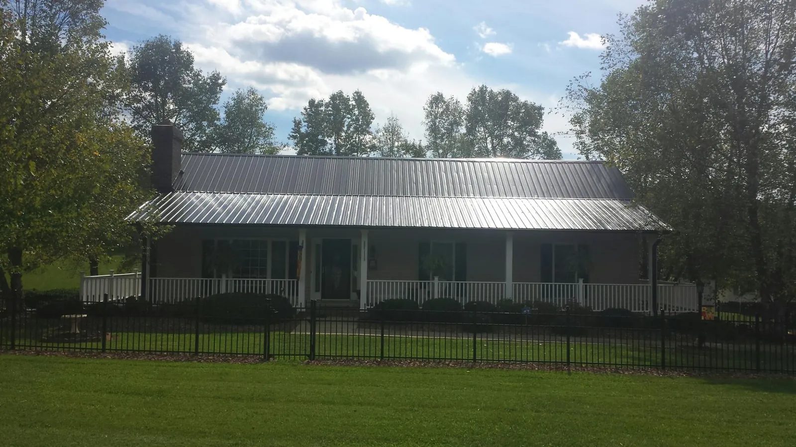 Gray metal roof on a brick ranch with a full width front porch — Gutter Guard Installation work by our crew in Huguenot