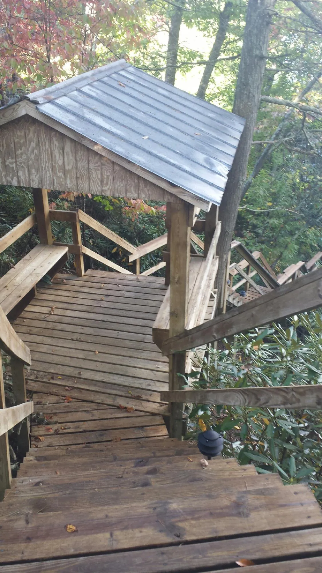 Metal roofed shelter over wooden steps on a wooded walkway — Skylight Repair & Installation work by our crew in Huguenot