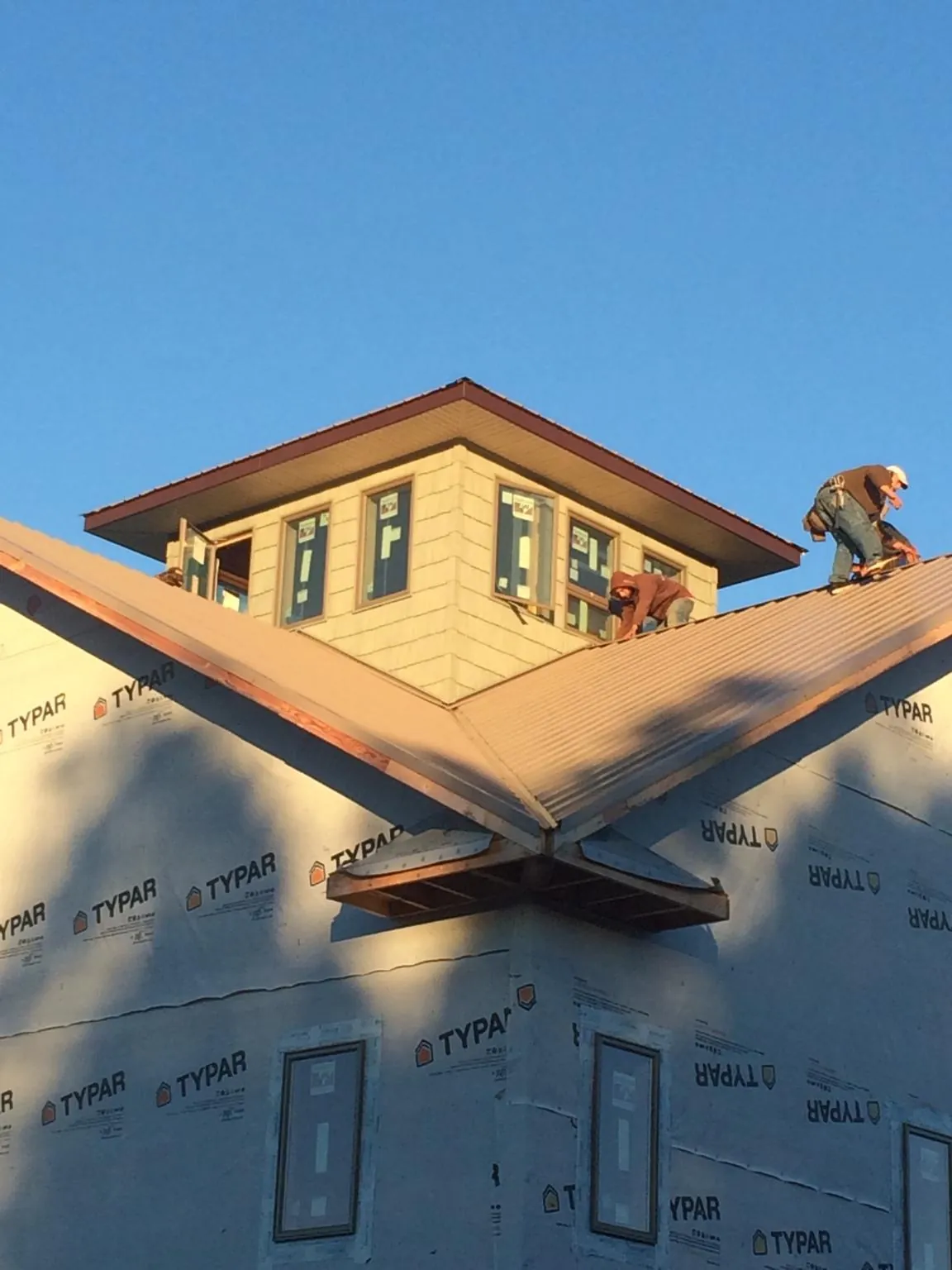 Roofers working around a rooftop cupola on a new metal roof at sunset — Roof Waterproofing in Huguenot by Roofing Brothers
